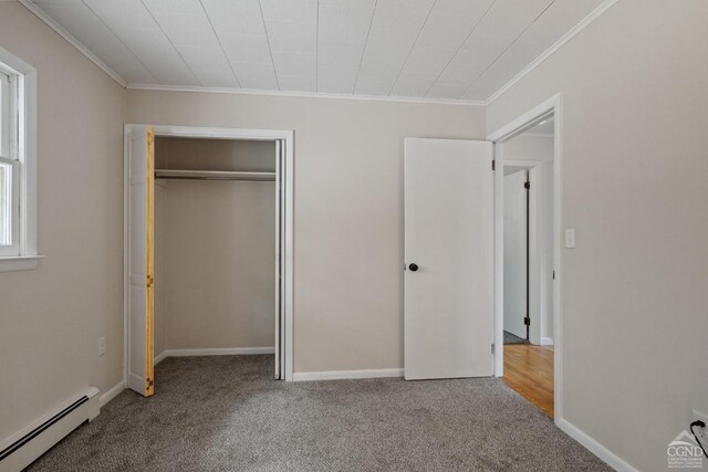 unfurnished bedroom with carpet floors, a closet, baseboard heating, and ornamental molding