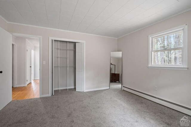 unfurnished bedroom with baseboard heating, light carpet, a closet, and ornamental molding