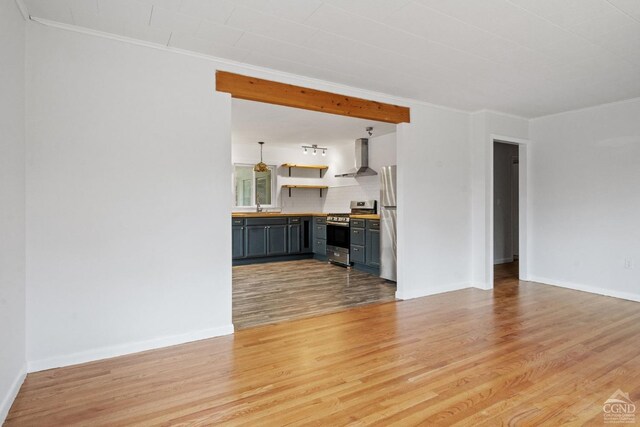 unfurnished living room with light wood-type flooring, ornamental molding, and sink