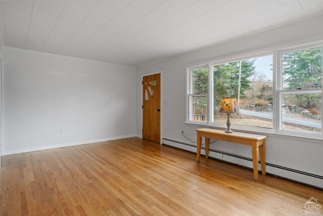 unfurnished room featuring light hardwood / wood-style flooring, plenty of natural light, and a baseboard heating unit