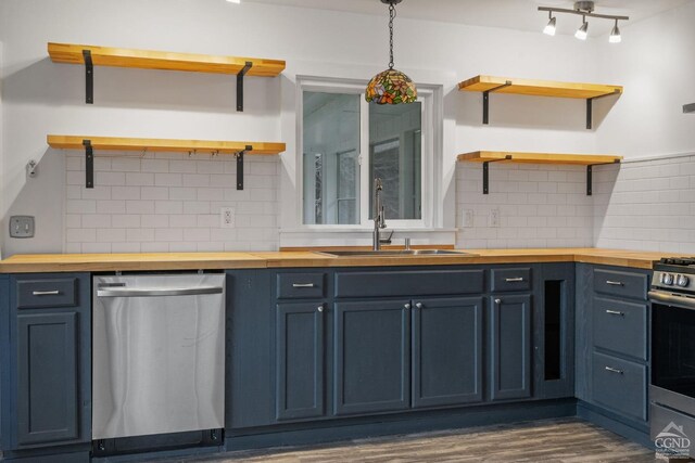 kitchen with blue cabinetry, pendant lighting, stainless steel appliances, and butcher block counters