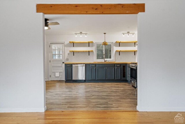 kitchen featuring appliances with stainless steel finishes, backsplash, sink, pendant lighting, and light hardwood / wood-style flooring