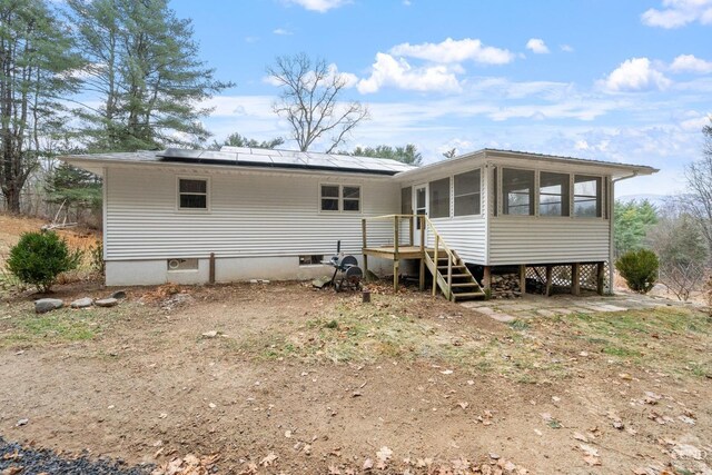 rear view of property featuring a sunroom and solar panels