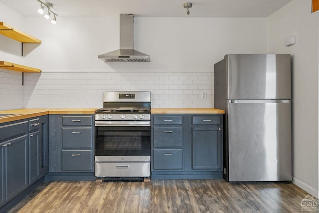 kitchen with butcher block counters, wall chimney range hood, appliances with stainless steel finishes, and tasteful backsplash