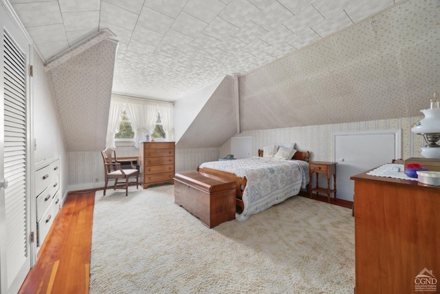 bedroom with vaulted ceiling and wallpapered walls