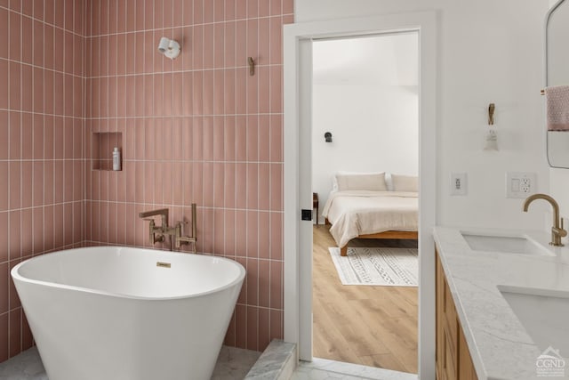 bathroom with a tub to relax in, vanity, tile walls, and hardwood / wood-style flooring