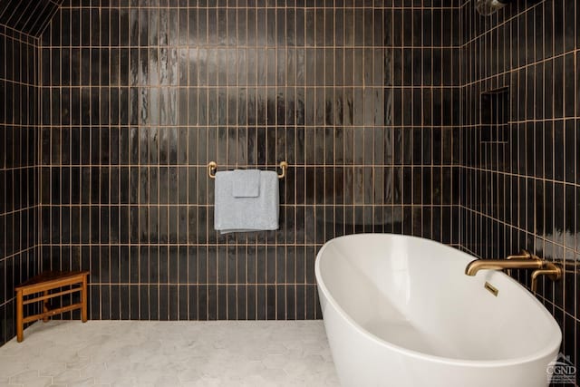 bathroom with tile patterned flooring, a bathing tub, and tile walls