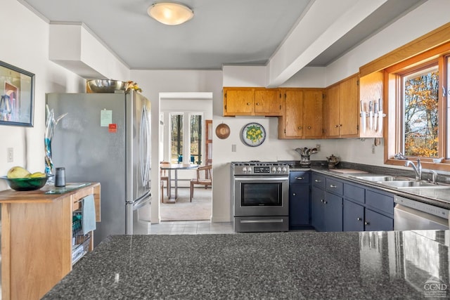 kitchen with dark stone countertops, sink, light tile patterned floors, and stainless steel appliances