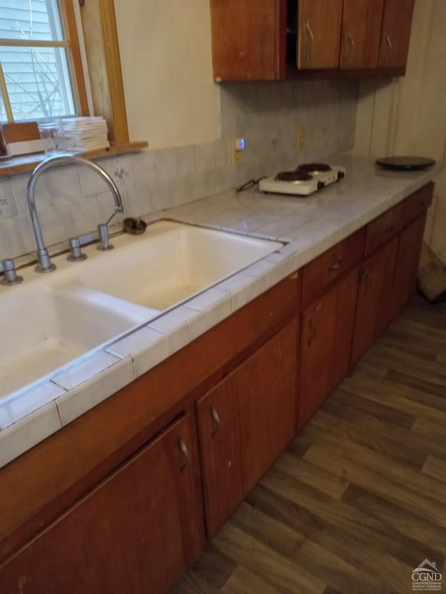 kitchen featuring backsplash, tile counters, dark wood-type flooring, and sink