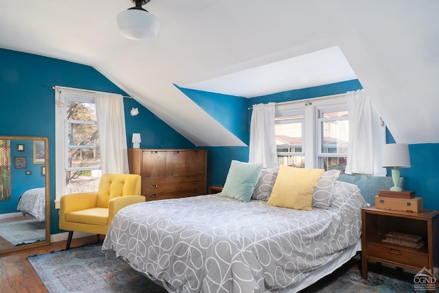 bedroom featuring wood finished floors, lofted ceiling, and baseboards