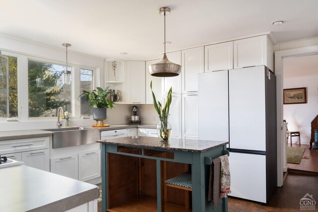 kitchen featuring freestanding refrigerator, decorative light fixtures, open shelves, white cabinets, and a sink