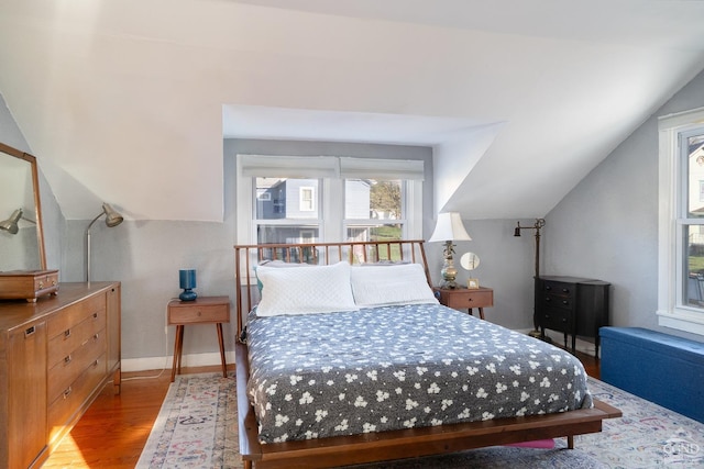bedroom with wood finished floors, vaulted ceiling, and baseboards