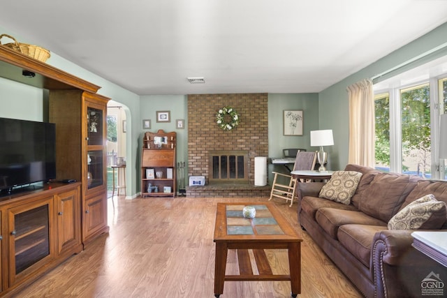 living room with a brick fireplace and light hardwood / wood-style flooring