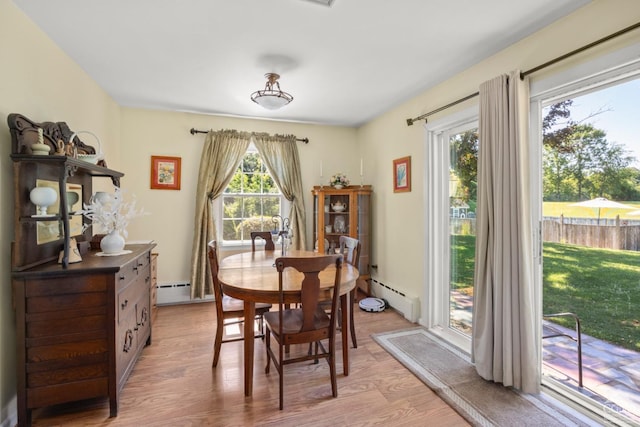 dining space with a baseboard radiator, a healthy amount of sunlight, and light hardwood / wood-style floors