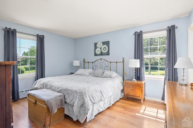 bedroom featuring light hardwood / wood-style floors and a baseboard heating unit