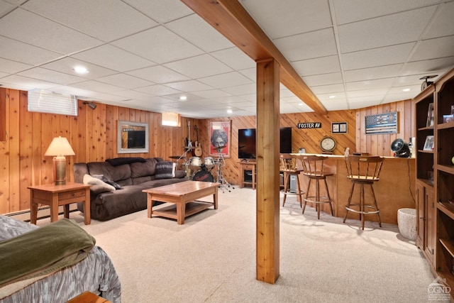 living room featuring carpet, a paneled ceiling, and wood walls