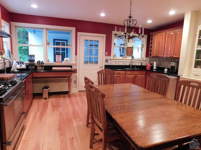 kitchen with tasteful backsplash, sink, a chandelier, radiator heating unit, and stainless steel gas stove