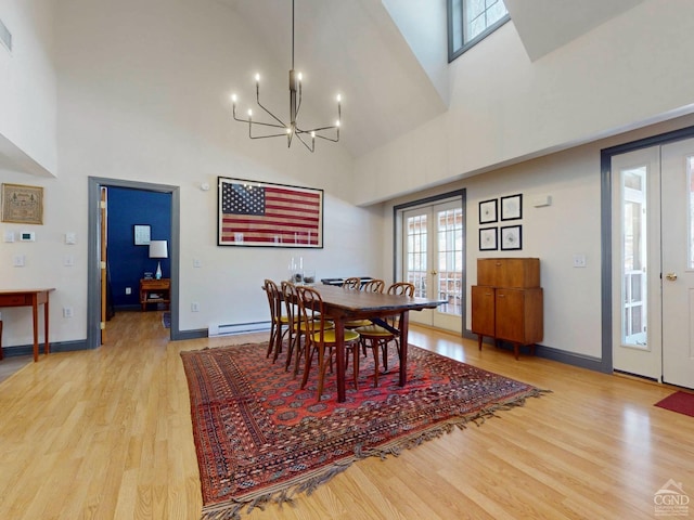 dining area with french doors, a notable chandelier, light wood-style flooring, high vaulted ceiling, and baseboards