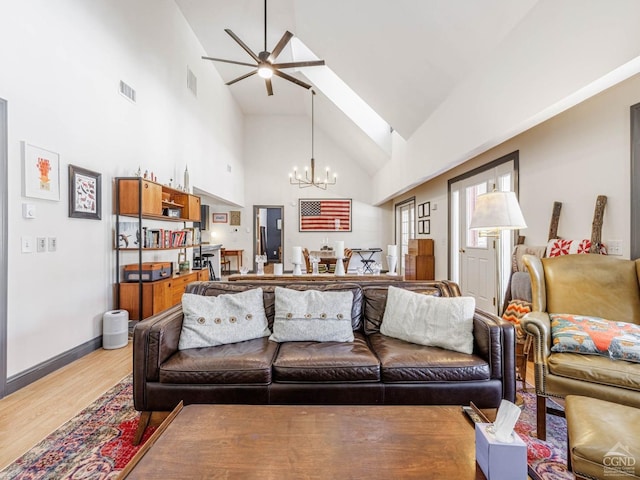 living room with high vaulted ceiling, visible vents, light wood finished floors, and ceiling fan with notable chandelier