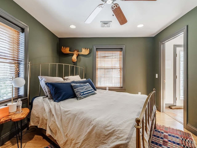 bedroom with wood finished floors, visible vents, ceiling fan, and multiple windows