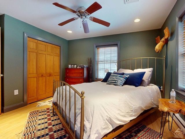 bedroom featuring light wood-style floors, a closet, baseboards, and a ceiling fan