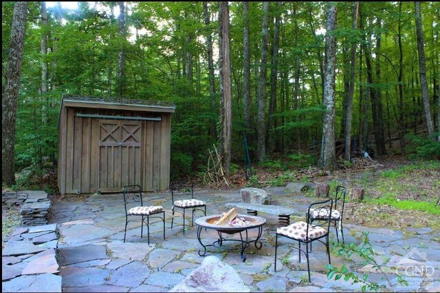 view of patio / terrace with a fire pit, a shed, and an outbuilding