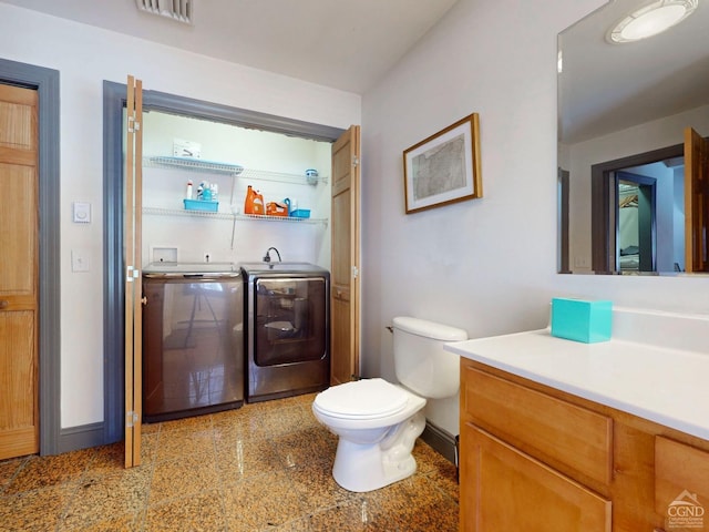 bathroom featuring toilet, separate washer and dryer, vanity, visible vents, and baseboards