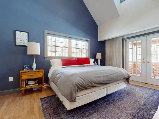 bedroom with access to outside, french doors, multiple windows, and wood finished floors