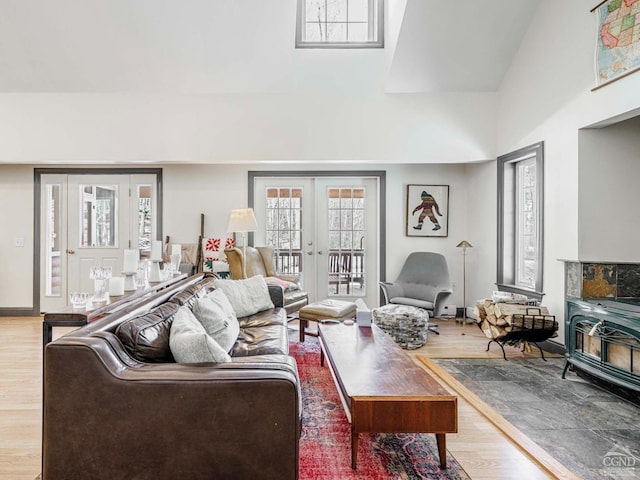 living area with high vaulted ceiling, french doors, wood finished floors, and a wood stove