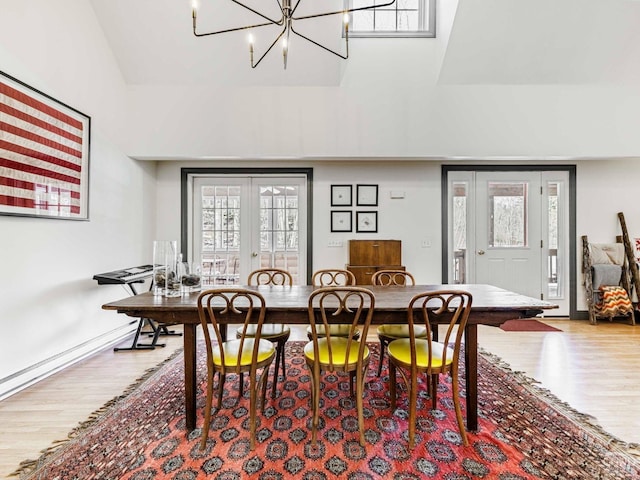 dining space with a chandelier, french doors, wood finished floors, and baseboards