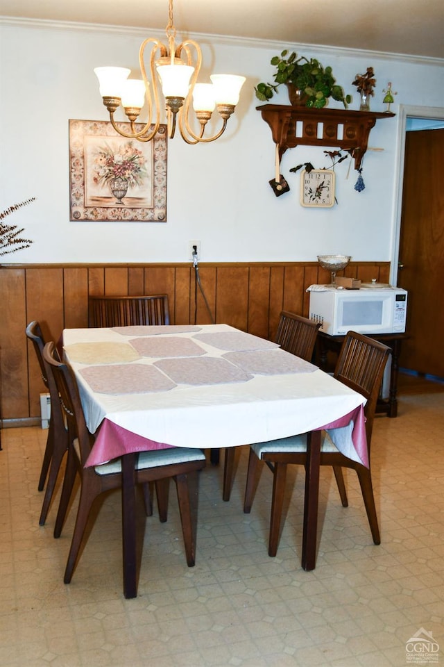 dining room featuring wooden walls, crown molding, and a chandelier