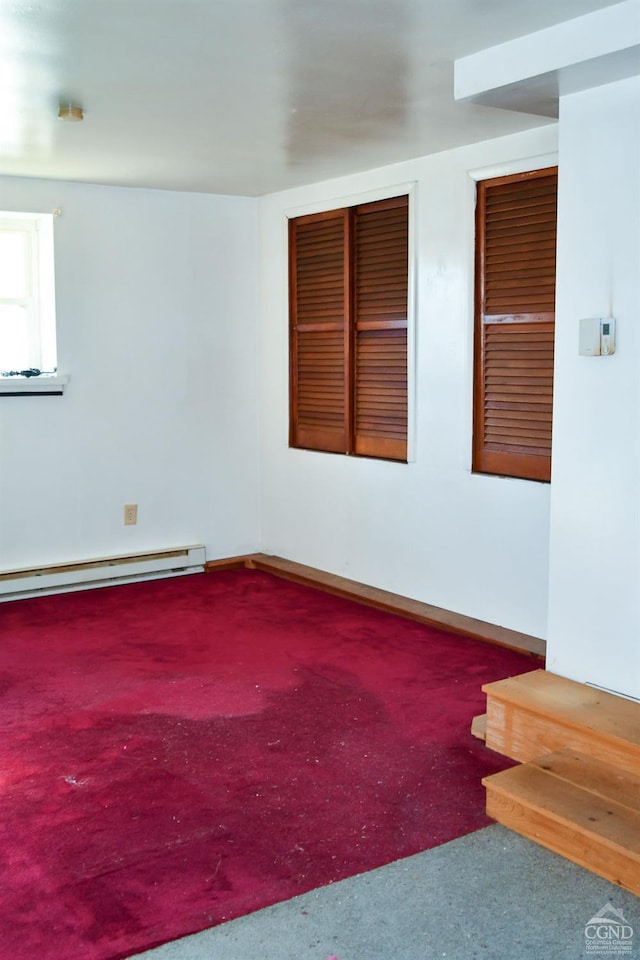 carpeted empty room featuring a baseboard heating unit