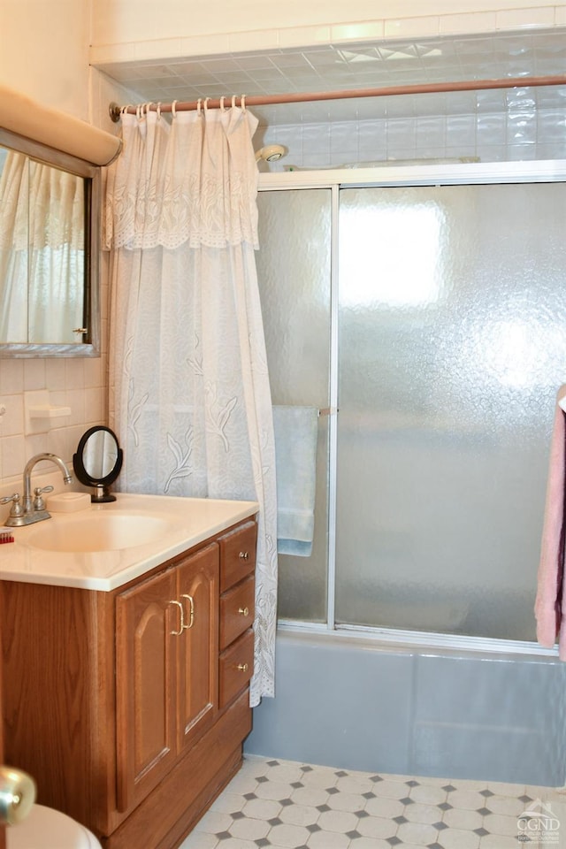 bathroom featuring decorative backsplash, vanity, and bath / shower combo with glass door