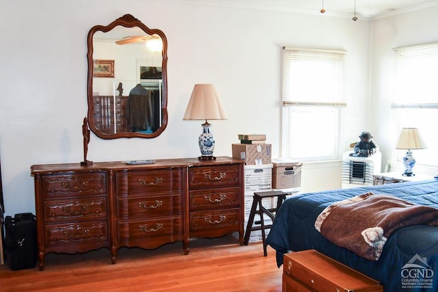 bedroom with light hardwood / wood-style flooring, multiple windows, and crown molding