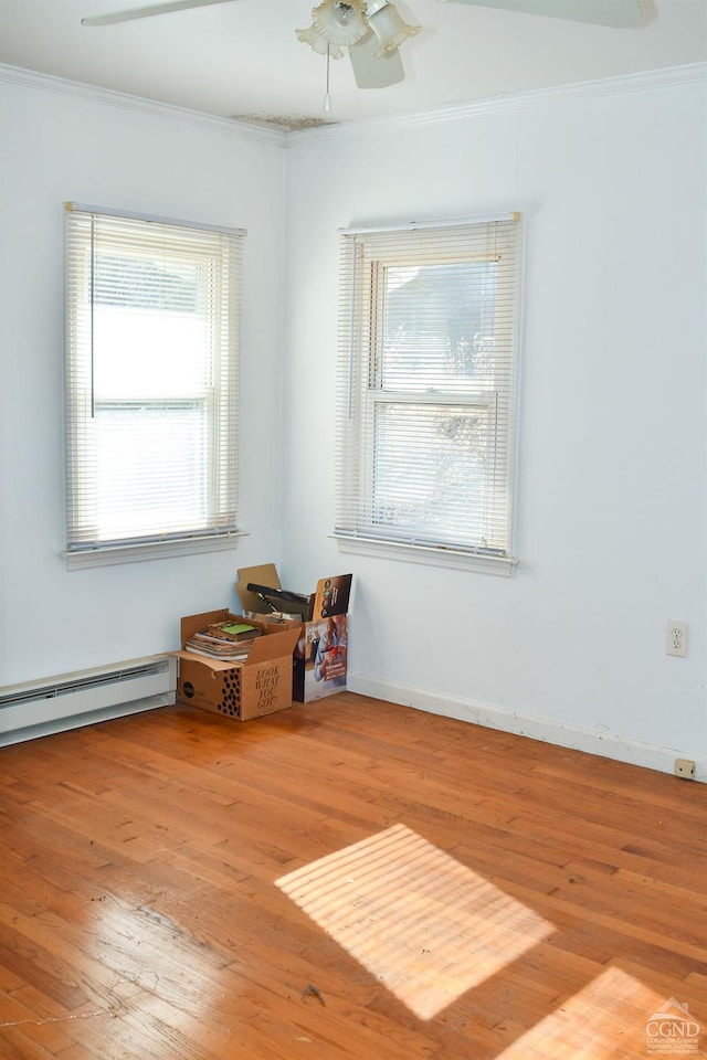 unfurnished room with hardwood / wood-style flooring, ceiling fan, crown molding, and a baseboard heating unit