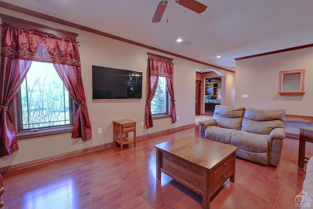 living room with ceiling fan, light wood-type flooring, and ornamental molding