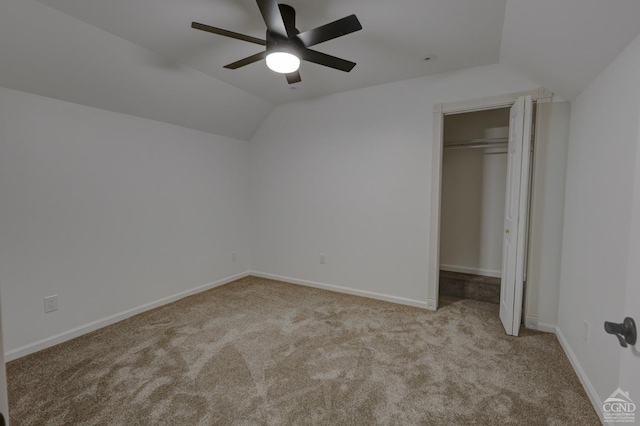 unfurnished bedroom featuring ceiling fan, a closet, light colored carpet, and lofted ceiling