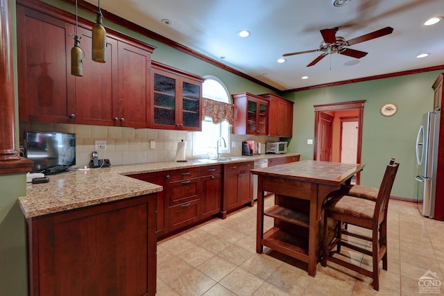 kitchen featuring pendant lighting, crown molding, decorative backsplash, ceiling fan, and appliances with stainless steel finishes