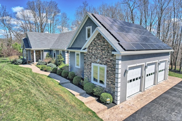 view of front of home with a front yard, solar panels, and a garage