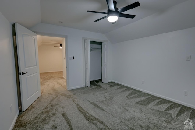 unfurnished bedroom featuring a closet, light colored carpet, vaulted ceiling, and ceiling fan