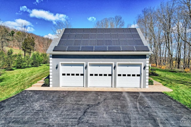 garage featuring solar panels and a lawn