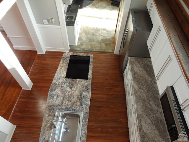 kitchen with light stone countertops, white cabinets, and dark wood-type flooring