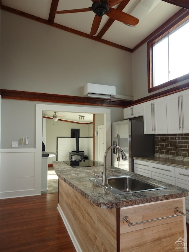 kitchen featuring a wall mounted air conditioner, stainless steel fridge, dark hardwood / wood-style flooring, sink, and white cabinetry