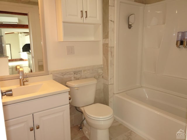 full bathroom featuring shower / bathing tub combination, vanity, tile walls, and toilet