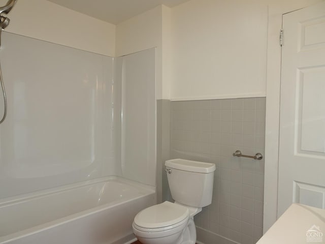 bathroom featuring shower / bathing tub combination, tile walls, and toilet