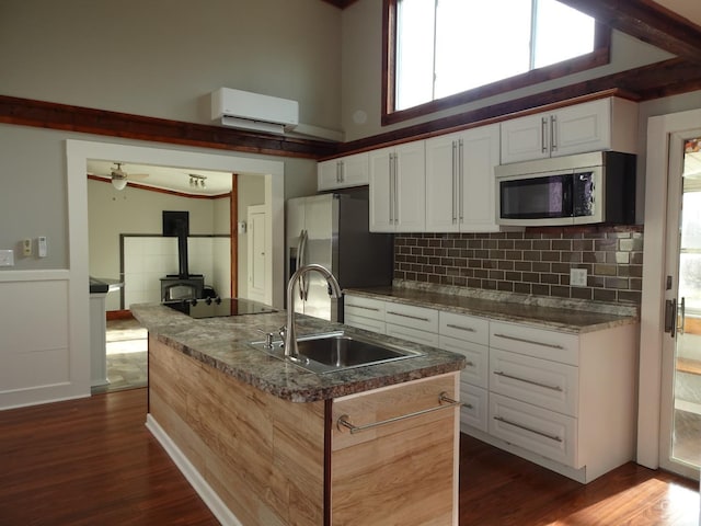 kitchen with stainless steel appliances, sink, a center island with sink, white cabinets, and dark hardwood / wood-style floors