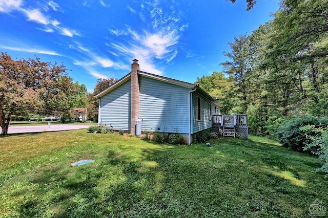 view of property exterior featuring a yard, a chimney, and a wooden deck