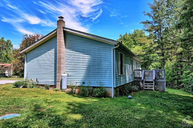 view of side of home with a chimney, a yard, and a deck