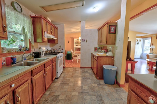 kitchen with under cabinet range hood, a sink, light countertops, and white range with gas cooktop