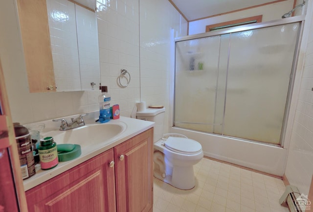 bathroom with tile walls, toilet, a baseboard heating unit, combined bath / shower with glass door, and vanity